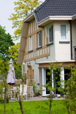 a house with chairs and an umbrella in the yard at Wellness Hasselt B&B in Hasselt