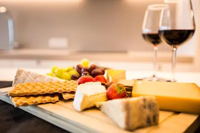 a plate of cheese and fruit with a glass of wine at Wellness Hasselt B&B in Hasselt
