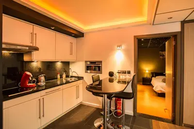 a kitchen with white cabinets and a table and a bedroom at Wellness Hasselt B&B in Hasselt