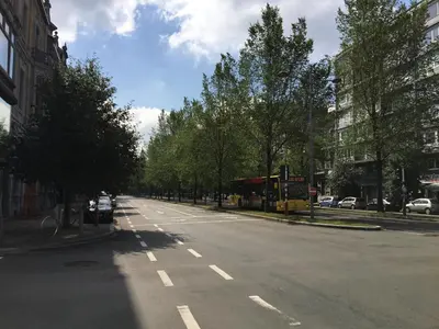 an empty city street with a bus on the road at DayNight Sauveniere in Liège