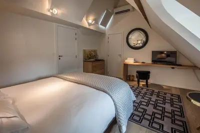 a bedroom with a white bed and a desk at Faubourg Saint Martin in Liège