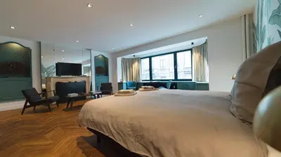 a bedroom with a large bed and a living room at B&B The Street Lodge in Liège