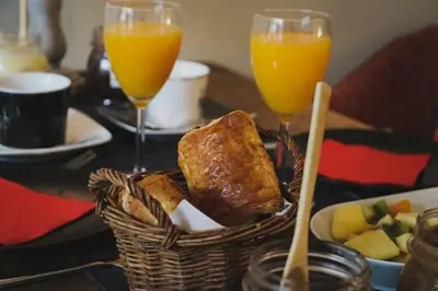 a table with a basket of bread and two glasses of orange juice at B&B The Street Lodge in Liège