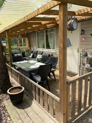 a wooden patio with a table and chairs on a deck at Chalet Sint-Hubertus in Zutendaal