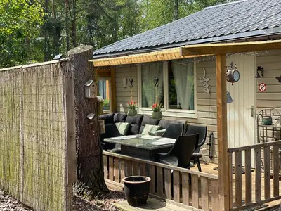a wooden deck with a table and chairs on a house at Chalet Sint-Hubertus in Zutendaal