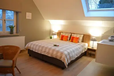 a bedroom with a bed with orange pillows at Maison Margriet in Tongeren