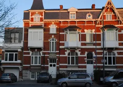 a large brick building with cars parked in front of it at B&B Villa des Roses in Hasselt