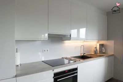 a white kitchen with white cabinets and a sink at De Vlier - Vakantiewoningen in Maasmechelen