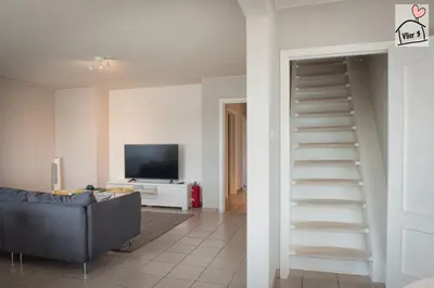 a living room with a staircase leading up to a tv at De Vlier - Vakantiewoningen in Maasmechelen