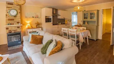 a living room with a white couch and a dining room at Chalet Relax in Zutendaal