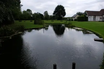 a river in a yard with a house in the background at Abeljano in Hasselt