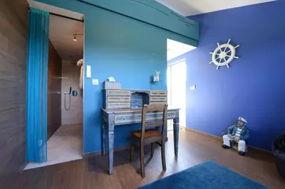 a child sitting at a table in a room with blue walls at Les Coteaux du Vinave in Herve