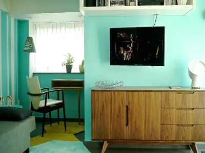 a living room with a tv on a blue wall at Gîte Au26 côté jardin-côté cour in Liège