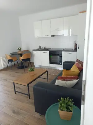 a living room with a blue couch and a kitchen at InContri in Liège