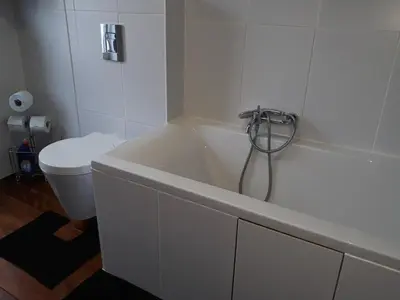 a white bathroom with a tub and a toilet at Cosy Corner in Lommel