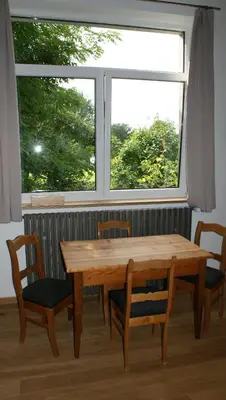 a wooden table and chairs in front of a window at Übernachten im ehemaligen Zollgebäude in Hauset