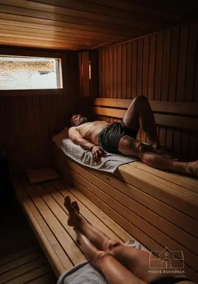 two men laying on beds in a sauna at Hoeve Roosbeek in Zepperen