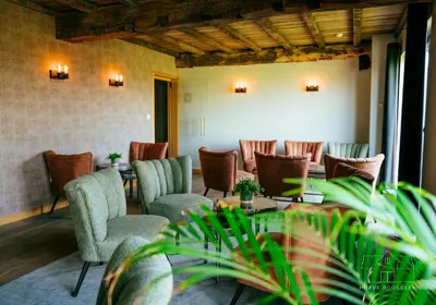 a restaurant with tables and chairs and plants at Hoeve Roosbeek in Zepperen