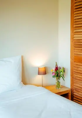 a bedroom with a white bed and a vase of flowers at Hoeve Roosbeek in Zepperen