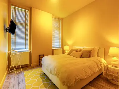 a bedroom with a large bed and two windows at Luxurious holiday home in Heers with terrace in Mettekoven