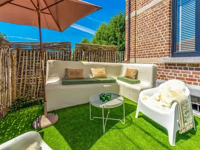 a patio with a couch and a table and an umbrella at Luxurious holiday home in Heers with terrace in Mettekoven
