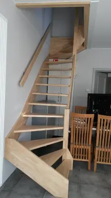 a wooden staircase in a room with two chairs at 't Hagerhuys in Maaseik