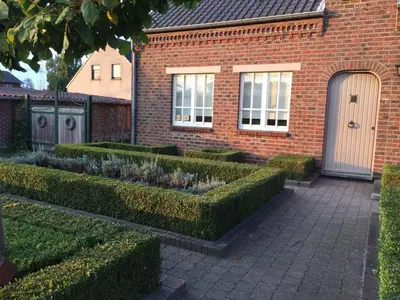 a brick house with hedges in front of it at 't Hagerhuys in Maaseik