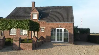 a red brick house with a white door at 't Hagerhuys in Maaseik