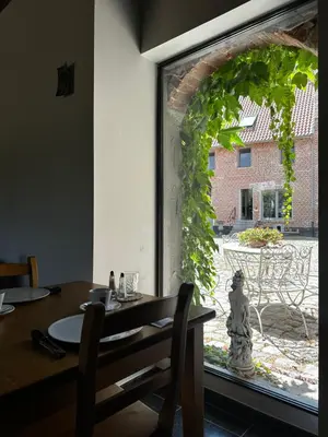 a dining room with a table and a large window at De Verborgen Parel B&B in Borgloon