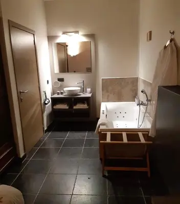 a bathroom with a tub and a sink and a mirror at De Verborgen Parel B&B in Borgloon