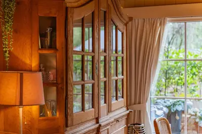 a wooden cabinet with glass doors in a room with a window at Chalet Luxe in Zutendaal