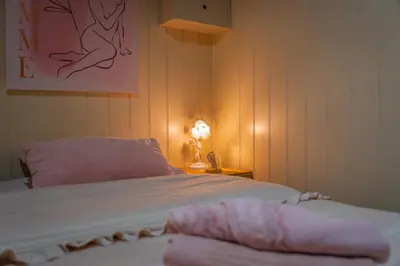 a bedroom with a bed with pink sheets and a lamp at Chalet Luxe in Zutendaal