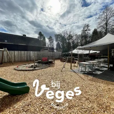 a playground with a green slide and tables and a building at Chalet Luxe in Zutendaal