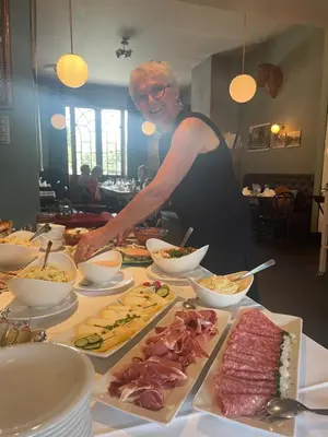 a man preparing food on a table with plates of food at PRET A GOUTER bistro bar bed in Heusden - Zolder