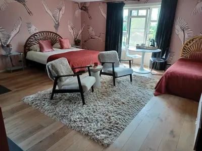 a bedroom with a bed and two chairs and a rug at Bed and breakfast Mooi Achel in Achel