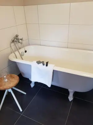 a white bath tub in a bathroom with a table at Bed and breakfast Mooi Achel in Achel