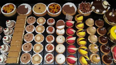 a display case filled with lots of different types of desserts at B&B Huize Briers in Bilzen