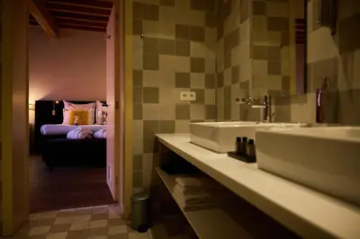 a bathroom with two sinks and a bedroom with a bed at B&B Huize Briers in Bilzen