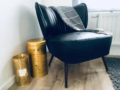a dark green chair with a blanket on it next to two gold buckets at L'Inizio Suite in Herve