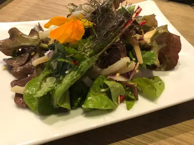 a white plate with a salad on a table at De Ruttermolen in Tongeren