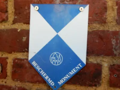 a blue and white sign on a brick wall at De Ruttermolen in Tongeren