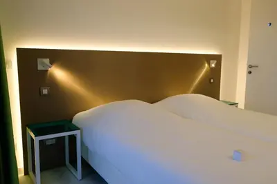 a bedroom with a large white bed and a night stand at Corbie Lommel Ring in Lommel
