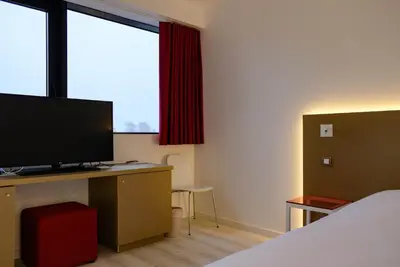 a bedroom with a bed and a desk with a television at Corbie Lommel Ring in Lommel
