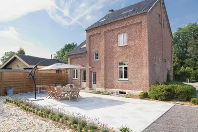 a brick house with a table and an umbrella at Vakantiewoning Tivoli in Dilsen-Stokkem