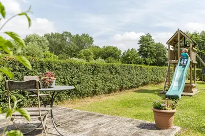 a garden with a playground and a girl on a swing at Vakantiewoning Tivoli in Dilsen-Stokkem