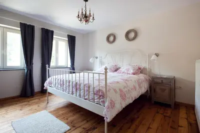 a bedroom with a white bed with pink sheets and a chandelier at Vakantiewoning Tivoli in Dilsen-Stokkem