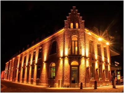 a large brick building with lights on it at night at Hotel De Boskar Peer in Peer