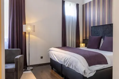 a hotel room with a bed and a chair at Hotel De Boskar Peer in Peer