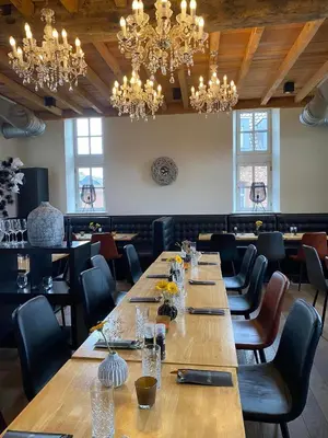 a row of tables in a restaurant with chandeliers at Hotel De Boskar Peer in Peer