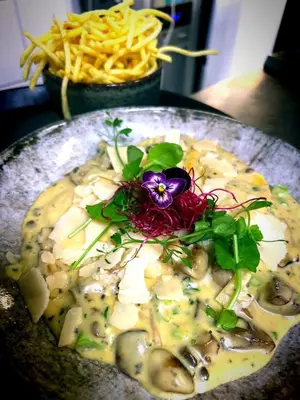 a bowl of soup with a purple flower on top at Hotel De Boskar Peer in Peer